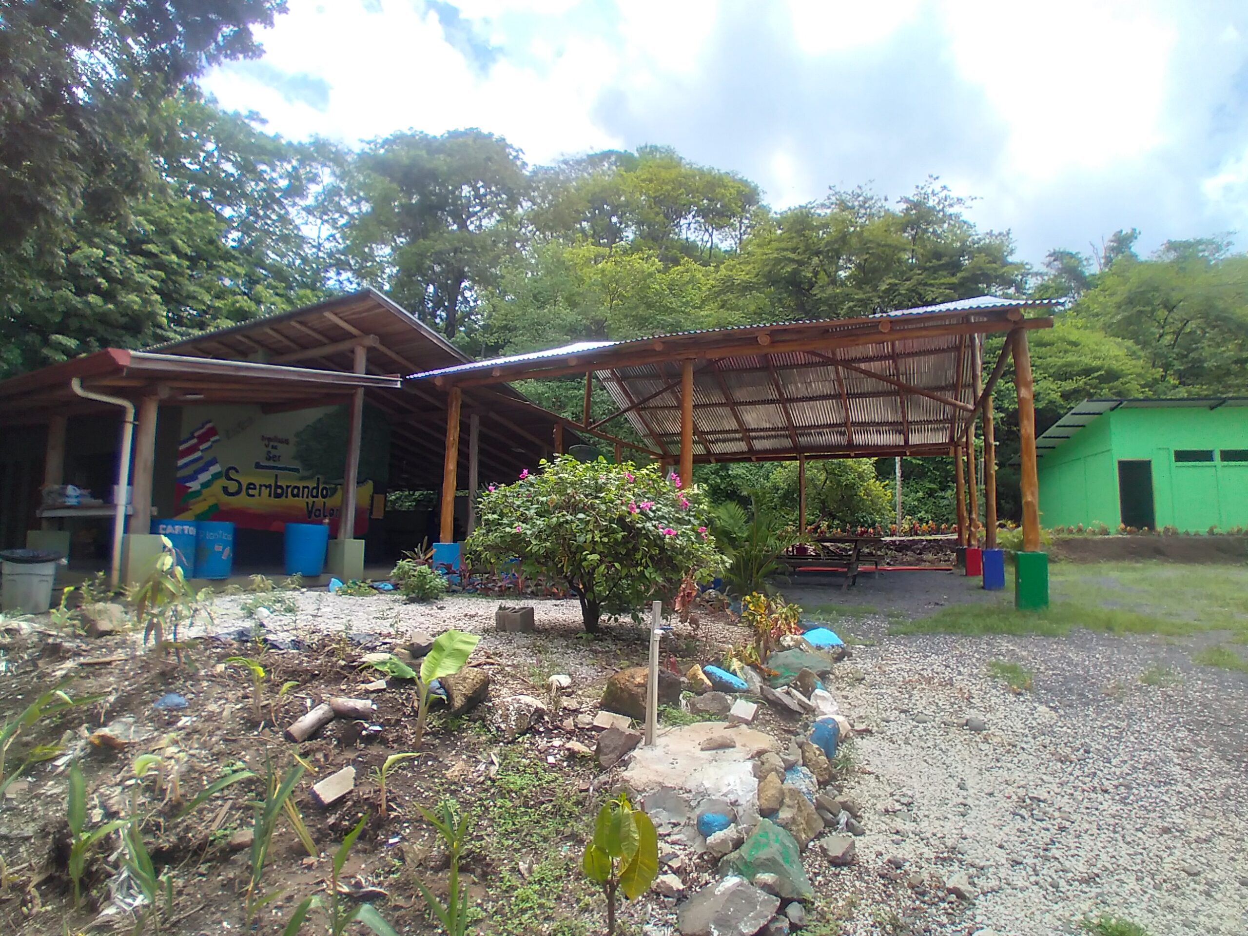 Ostional High School in Costa Rica. This image shows the front view of the school, which appears as a classroom with a large wooden shelter/pergola outside. © Connecting the Roots